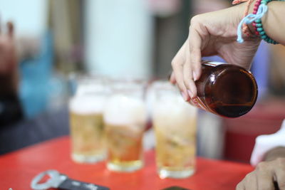 Midsection of person pouring beer into glasses