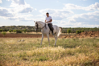 Full length of a young man riding horse on field