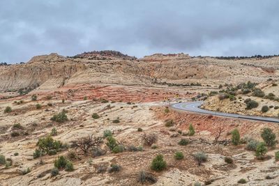 Scenic view of arid landscape against cloudy sky