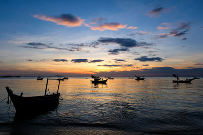 Silhouette boats in sea against sky during sunset