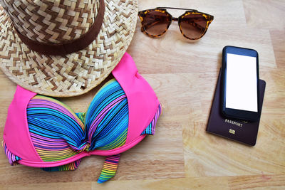 High angle view of mobile phone and passport with womenswear on hardwood floor