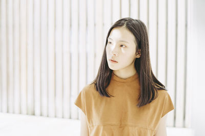 Close-up of young woman standing against wall