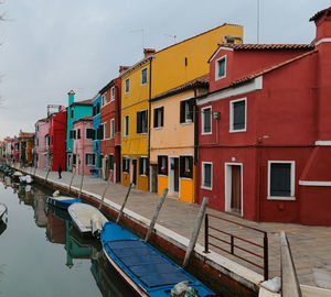 Boats moored in canal by buildings against sky in city