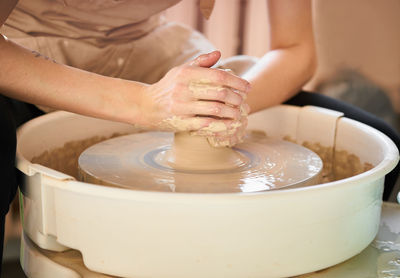 Midsection of potter making earthenware at pottery workshop