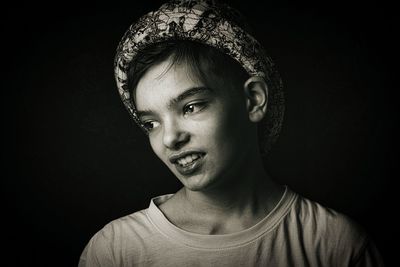 Close-up of teenage boy against black background