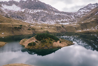 Scenic view of lake by snowcapped mountains against sky