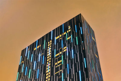 Low angle view of illuminated modern building against sky at dusk