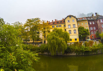 Houses by river and buildings against sky