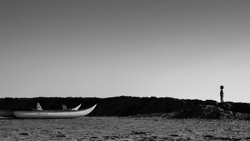 Boats moored at beach against clear sky