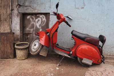 Red color motor scooter against wall