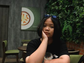 Portrait of woman with hand on cheek sitting at restaurant