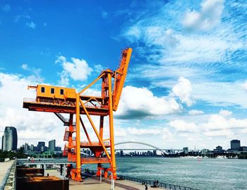 Cranes at commercial dock against sky