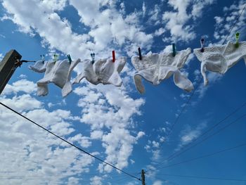 Low angle view of flags hanging against cloudy sky