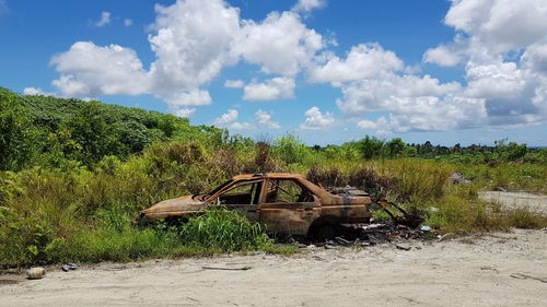 Abandoned vehicle on landscape against sky