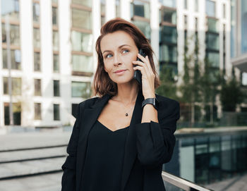 Young woman looking away while standing in city