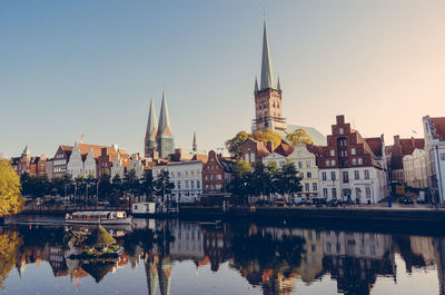 Buildings and church by river against sky in city