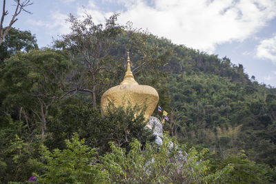 Rear view of buddha statue amidst trees in forest against sky