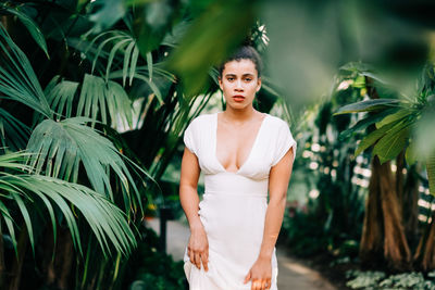 Young woman standing against plants