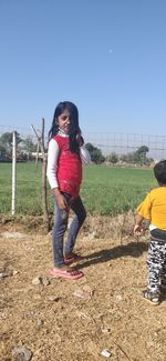 Full length of woman standing on field against clear sky