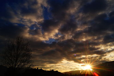 Low angle view of silhouette trees against dramatic sky