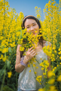 Portrait of woman standing amidst yellow flowers