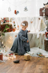 Cute baby toddler girl near the christmas tree with toys and garlands at home