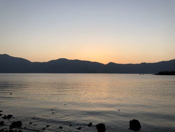 Scenic view of lake against clear sky during sunset