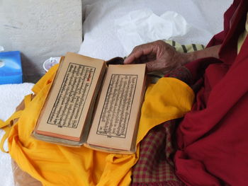 Midsection of monk reading religious book