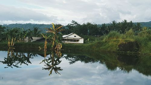 House by lake against sky