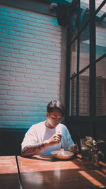 Portrait of boy sitting on table against window