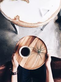 Midsection of person holding black coffee in wooden tray