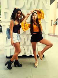 Full length portrait of woman standing against wall