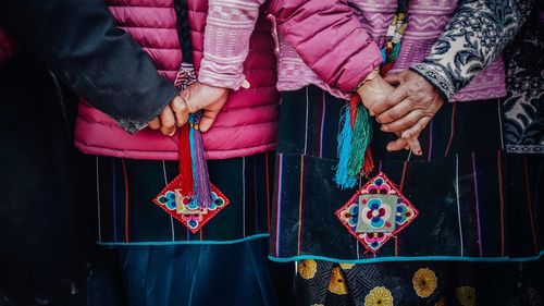 Midsection of women in traditional clothing while holding hands during tibetain new years day