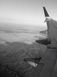 Cropped image of airplane flying over landscape against clear sky