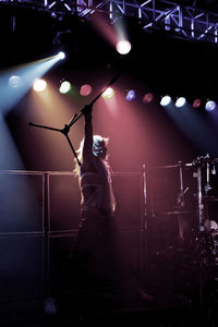 Man carrying microphone stand while standing on stage at concert