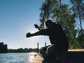 Man photographing with arms raised against sky