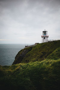 Lighthouse by sea against sky