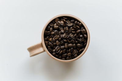 Coffee cup full of whole coffee beans