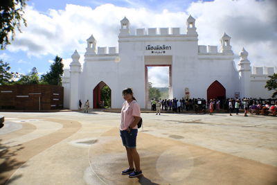 Woman standing against historic gate in city