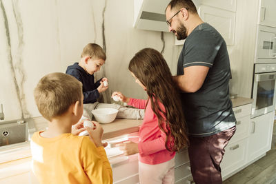 Man with children preparing breakfast in kitchen