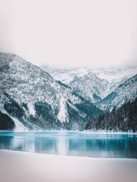 Scenic view of lake by snowcapped mountains against sky