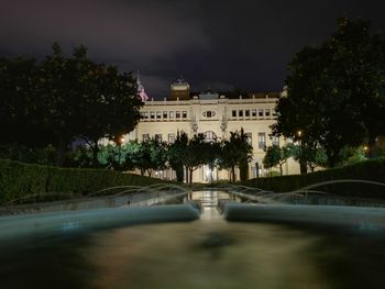 Road by illuminated building against sky at night