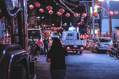 Rear view of woman standing on street at night