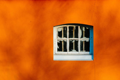 Close-up of abandoned window on orange wall