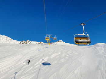 Ski lift over snowcapped mountain against clear sky