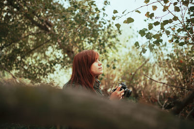 Young woman using mobile phone in tree