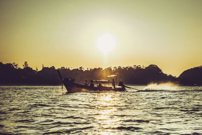 Silhouette boat sailing on sea against clear sky during sunset