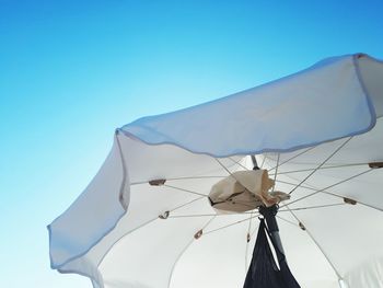 Low angle view of umbrella against clear blue sky