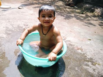 Portrait of smiling baby boy bathing in tub at yard