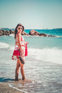 Portrait of young woman standing at beach